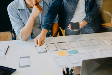 Website designer planning application development draft template layout framework and coding program on paper and computer.