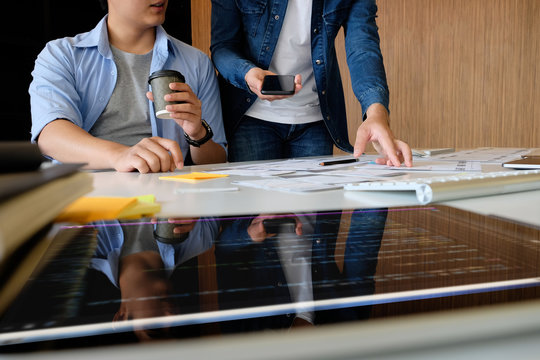 Website designer planning application development draft template layout framework and coding program on paper and computer.