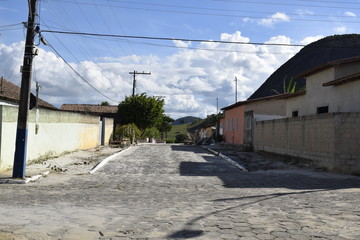 Rua de cidade com colina preta ao fundo