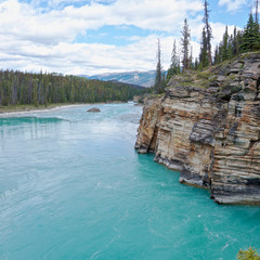 Turquoise river Athabasca flowing down from the glaciers at summer. The river goes around picturesque rocks. Jasper National Park, Icefields Parkway, Athabasca Falls. Square view.
