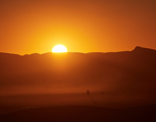 big sun setting in the desert full of dust