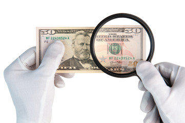Hands in white gloves with magnifier over 50 dollars banknote isolated on white background....