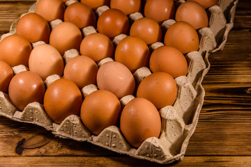 Pile of the hen eggs in paper tray on wooden table