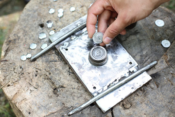 hand holding minted roman coin on a minting device