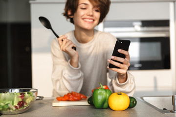 Image of Smiling brunette woman using smartphone