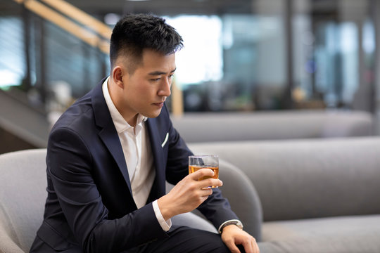 Young businessman drinking alcohol in office 