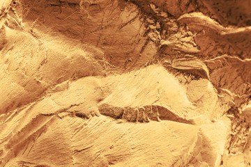 Vintage yellow background. Rough painted wall of aspen gold color. Imperfect plane of golden colored. Uneven old decorative toned backdrop of yellow tint. Texture of gold hue. Ornamental stony surface