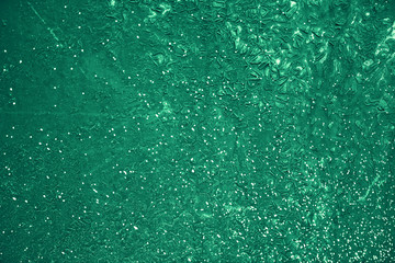 Vintage green background. Rough painted wall of emerald color. Imperfect plane of virid colored. Uneven old decorative toned backdrop of green tint. Texture of emerald hue. Ornamental stony surface.