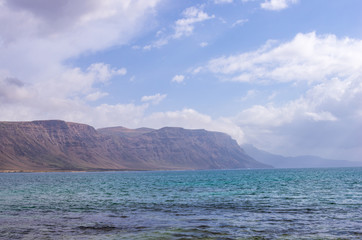 Plakat Cliffs of Lanzarote seen from a beach on the island of La Graciosa
