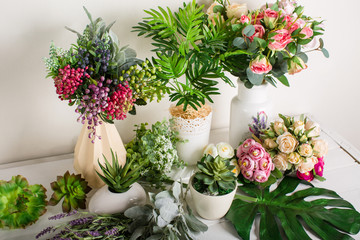 Various artificial flowers, bouquets in vases, succulents