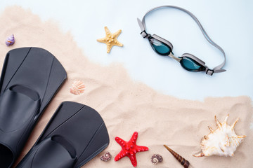 Swimming goggles and flippers on the sand with shells and starfishes. © nuclear_lily
