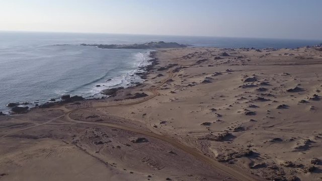 Las Tortolas beach aerial footage at Atacama Desert the sunset ray lights illuminate this amazing and idyllic beach in the middle of the desert, an arid awe landscape crashed by Pacific Ocean waters