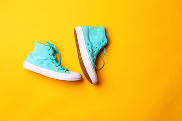 Pair of stylish sneakers laing on yellow background