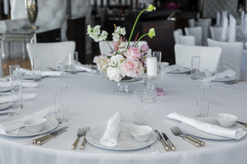 served table in the restaurant. clean white dishes layout on a white tablecloth