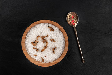 Gourmet spices. A bowl of sea salt infused with truffle shavings and a pepper mix, shot from above on a black background with a place for text