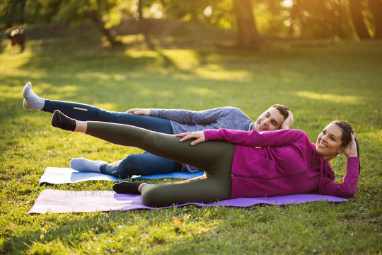 Couple Is Exercising In Park. Exercise For Sciatica Recovery.