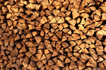 Background of dry chopped firewood, stacked wood trunks for winter heating fireplace.