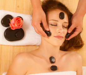 Obraz na płótnie Canvas attractive young beautiful woman having facial massage with mineral stone