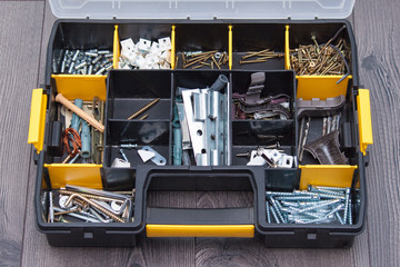 Plastic case with hardware items, closeup. Box with nails, screws, bolts, dowels.