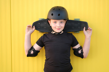 Young boy holding a skateboard on arms.