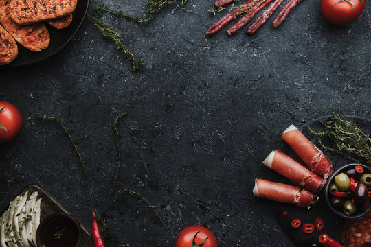 Mix of mediterranean appetizers. Jamon, chorizo, fuet and anchovy fillets on dark background with copy space.