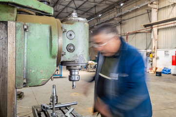 Blue-collar worker using milling machine in workshop