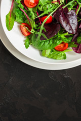 salad with tomato, lettuce, arugula, spinach and other leaves. food background. top