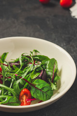 salad with tomato, lettuce, arugula, spinach and other leaves. food background. top