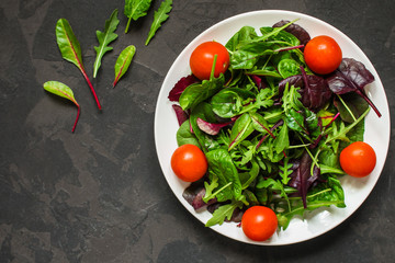 salad with tomato, lettuce, arugula, spinach and other leaves. food background. top
