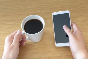 スマートフォンを操作しながらコーヒーを飲む