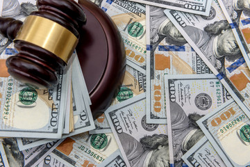 On the background of dollars are dollars, and on them lies hammer of the judge, close up