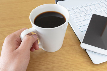 Obraz na płótnie Canvas ノートパソコンを操作しながらコーヒーを飲む
