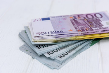 Euro banknotes in pile on light wooden background