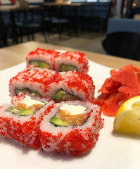 California beautiful sushi with red caviar on a plate in cafe with lemon