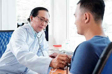 Obraz premium Doctor checking heartbeat of patient