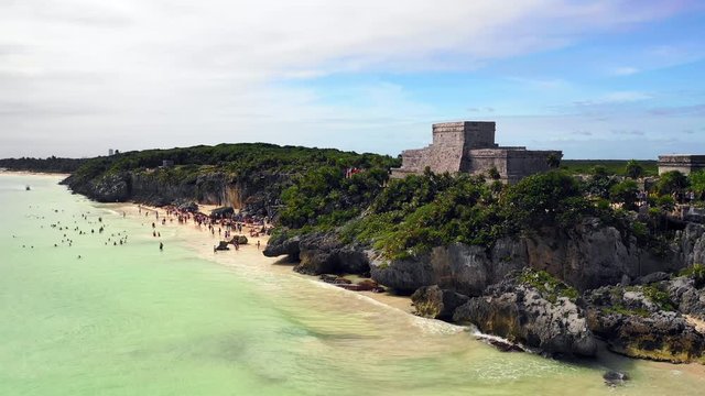 Aerial Pan Left: Stone Ruins On Cliff By Green Ocean Shore in Tulum, Mexico