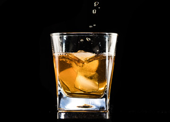 whiskey with ice in a steaming glass on a black background