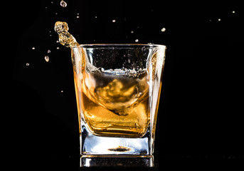 whiskey with ice in a steaming glass on a black background