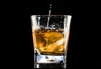 whiskey with ice in a steaming glass on a black background
