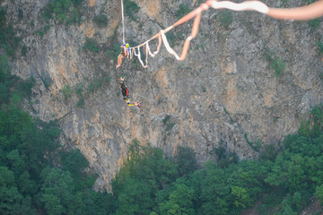 a man with a parachute and his friend jumping from a highline above the Red Lake, Split-Dalmatia,...