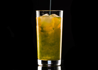 orange cocktail with mint syrup with ice in a glass on a black background