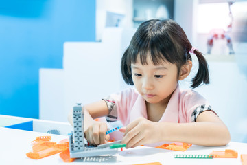 asian girl child having fun playing with colorful plastic blocks indoor at play school