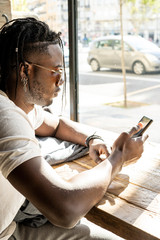 Handsome african american looking at a mobile phone in a coffee shop