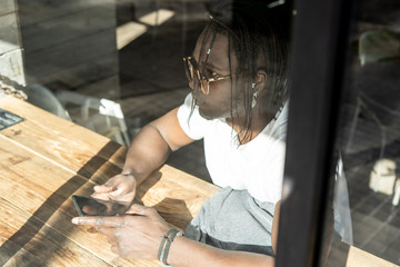 Handsome african american looking at a mobile phone in a coffee shop