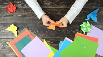Man folding an origami fox. Hands fold animal from paper, top view. Origami project ideas. Japan...