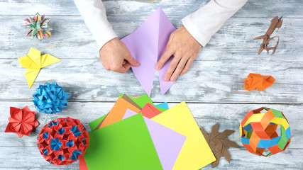 Making origami purple triangle. Wooden desk surface background.