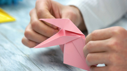 Close up man folding pink origami frog. How to make easy origami frog instructions. Japanese art of...