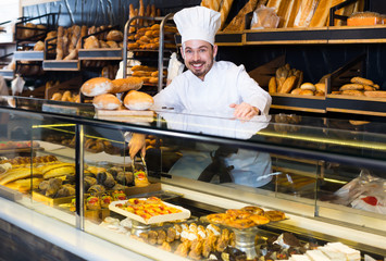 Cheerful baker showing assortment of bakery