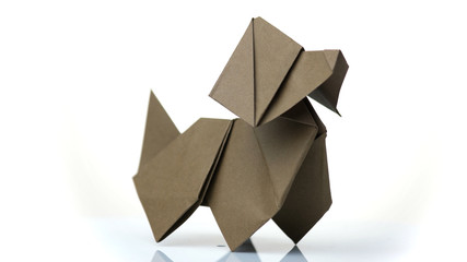 Paper dog figurine on white background. Origami dog made by child. Simple design of paper animal.