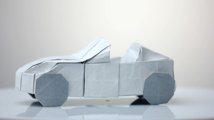 Origami car model on white background. Exhibition of paper decorations. - obrazy, fototapety, plakaty